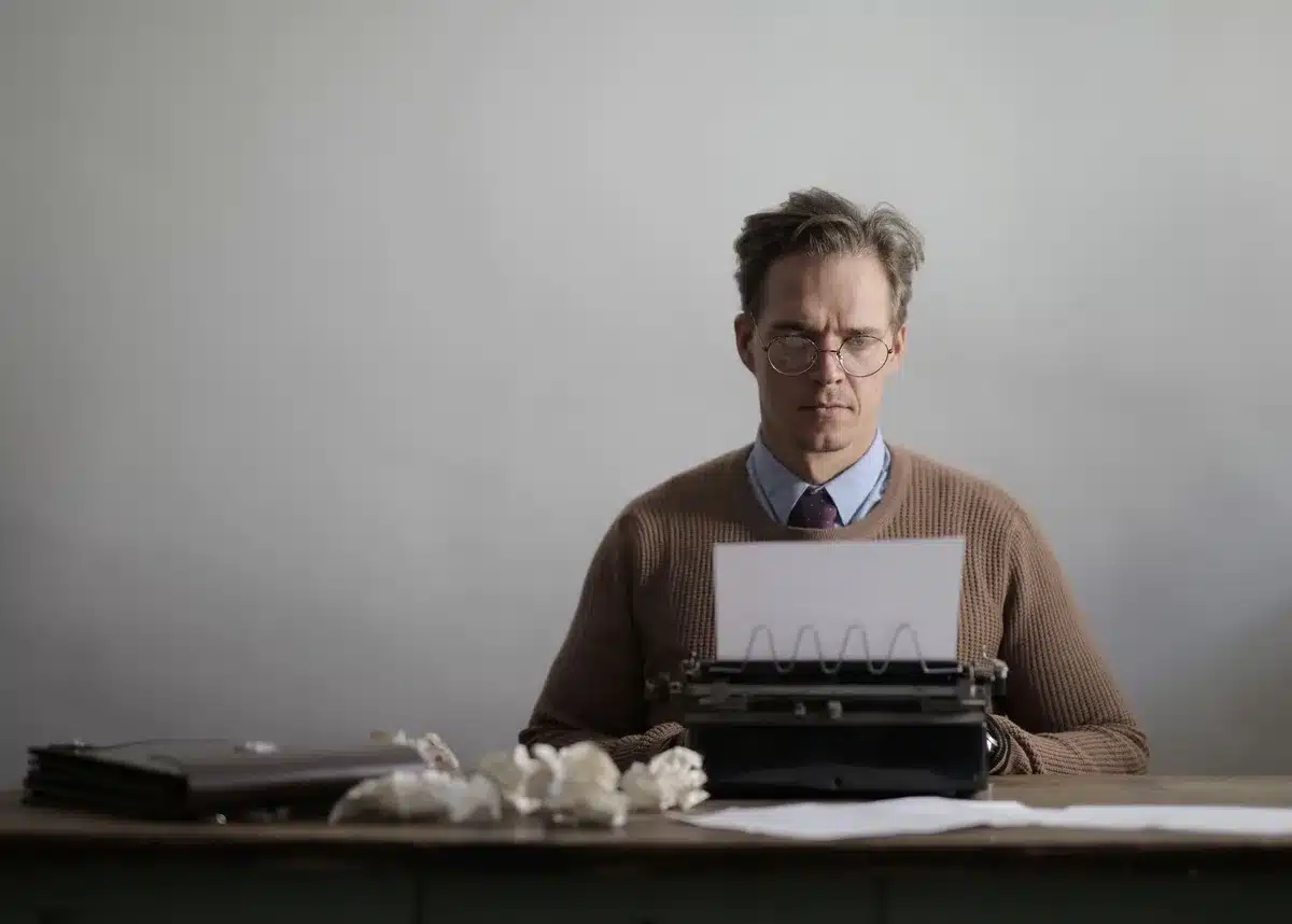 A person working at a desk with writing materials and notes, representing creative writing pursuits.
