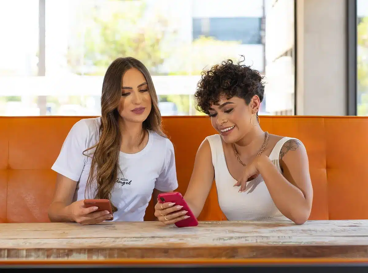Grupo de amigos conversando en una cafetería, gesto de complicidad