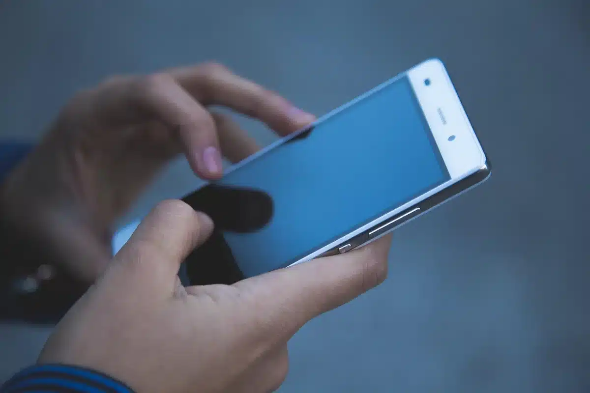 Hand holding a phone showing a side-scrolling action game with touch controls