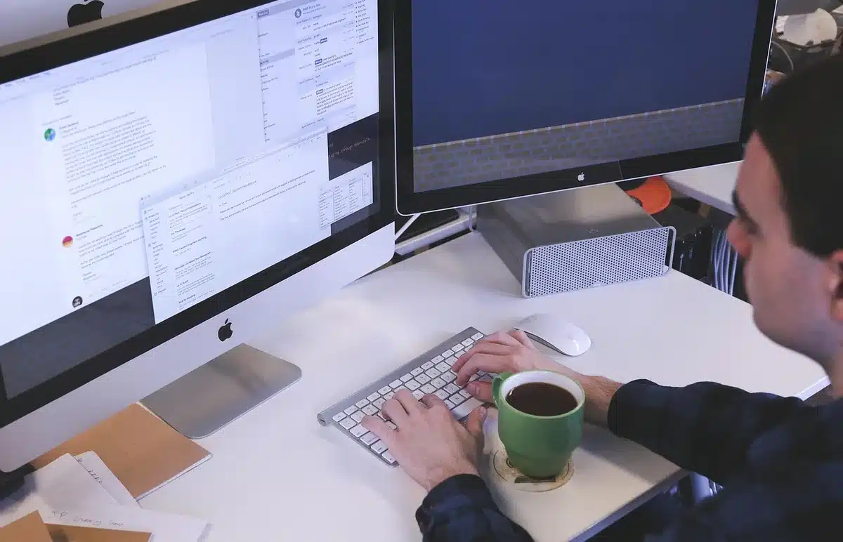 Person at a desk working with 3D models and code on a computer screen
