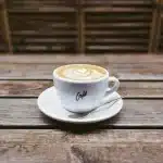 Manos anónimas sobre una mesa de café con un guion y una cámara desechable